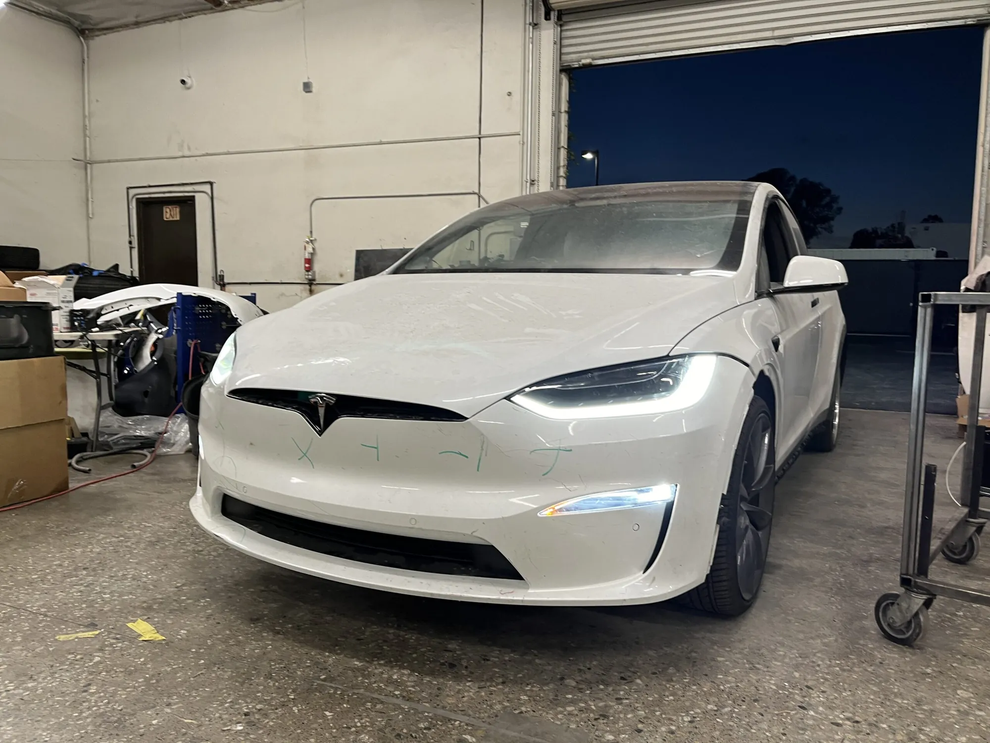 White Tesla Model X front bumper marked for repair assessment at TSK collision shop