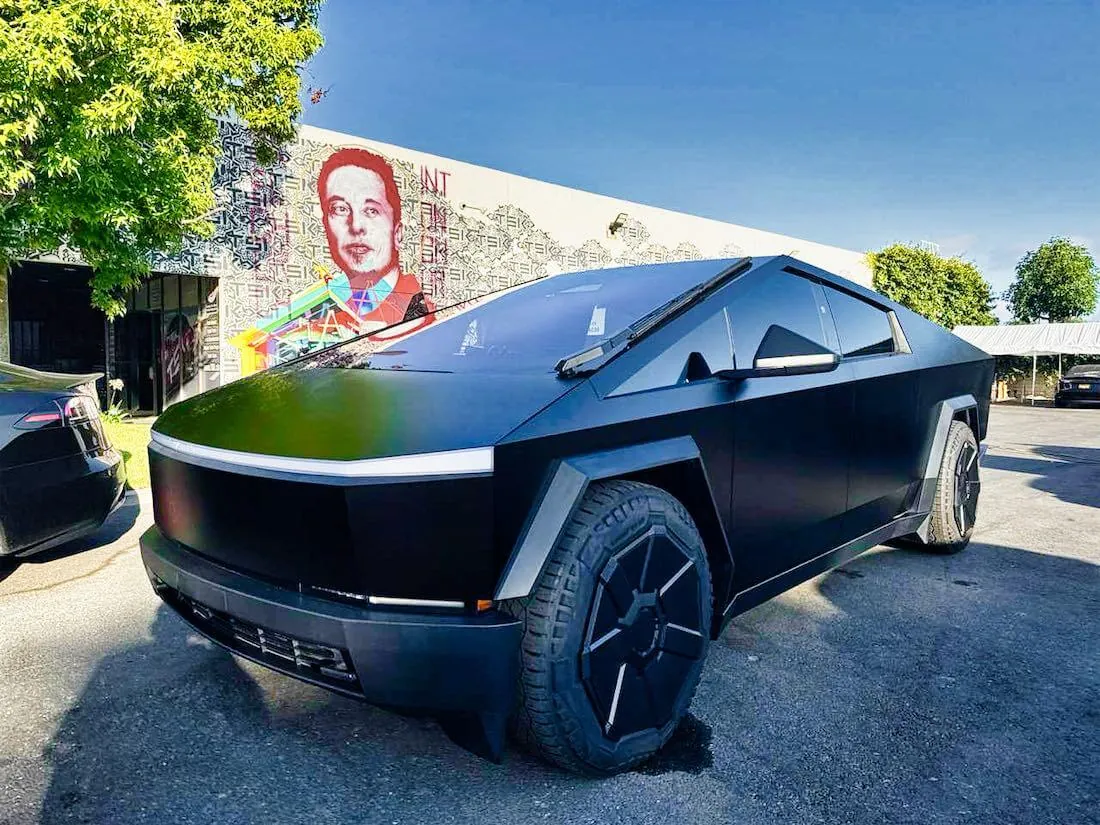 Matte black Tesla Cybertruck parked outside TSK EV collision repair shop in California